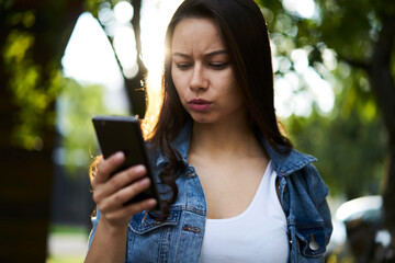 Puzzled Caucaisan hipster girl using cellular application for checking account balance via banking...