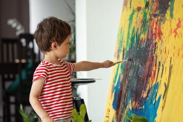 Little boy draw and art with brush and paints at home