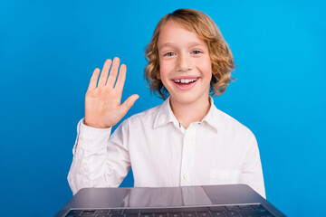 Portrait of handsome trendy cheerful boy making video call waving hi hello isolated over bright blue color background