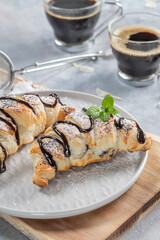 Homemade croissant served with black coffee or americano. Delicious breakfast with fresh croissant and coffee. Croissant and black coffee and chamomile with copy space in top view or flat lay style.