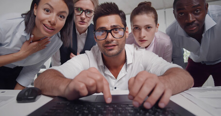 Multiethnic group of colleagues analyzing data looking at laptop screen working together in office