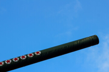 The barrel of a large-caliber artillery gun. Five-pointed stars on the trunk. Soviet weapons. Military equipment. The muzzle is directed to the right and up