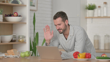 Fototapeta premium Man doing Video Call on Laptop in Kitchen