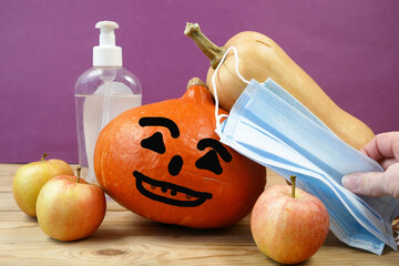 pumpkins, face masks for protection from coronavirus, sanitizer with halloween face jack-o-lantern....