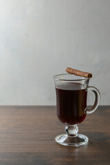 Mulled wine in glass cups with cinnamon and oranges on a wooden table.