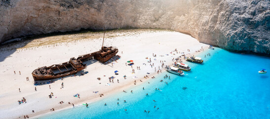 The beautiful Navagio shipwreck beach with turquoise sea and tourists enjoying the sea, Zakynthos island, Greece