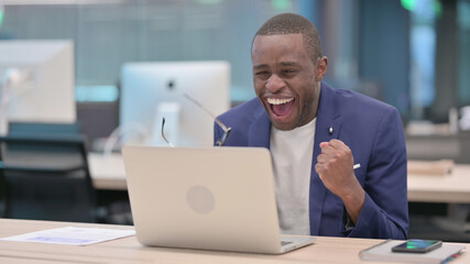 Fototapeta na wymiar Successful Young African Businessman Celebrating on Laptop at Work