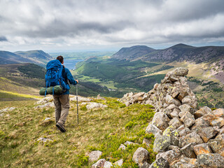 A hiker by a dry stone wall in the Lake District, Cumbria, England.