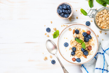 Yogurt granola with fresh blueberries on white wooden table. Top view with copy space. Healthy food, snack or breakfast.