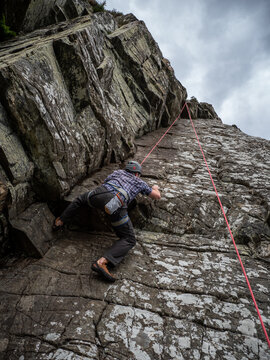 A man climbing a cliff face in Kingussie, Scotland.