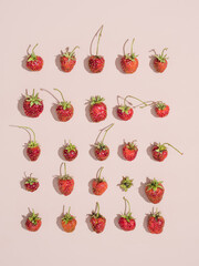 Strawberries with cuttings create a pattern. The berries are in a straight line. View from above. Powdery background. Flat lay. Summer pattern. Hard light. Bright shadows