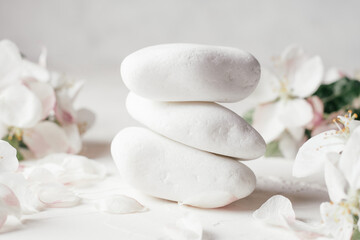 Fototapeta na wymiar Stack of white pebble stones on light plaster surface, with apple flowers