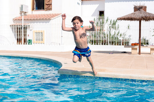 Little boy jumping into the water of the pool