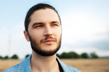 Fototapeta premium Close-up portrait of handsome young man, on the background of blue sky.