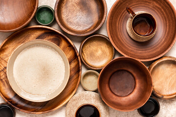Many different ceramic and wooden plates and bowls on a beige background top view. Flat lay. Background from empty plates and bowls.  Various empty dishes.