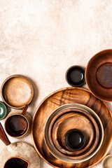 Many different ceramic and wooden plates and bowls on a beige background top view. Flat lay. Background from empty plates and bowls. Free space for text. Various empty dishes.