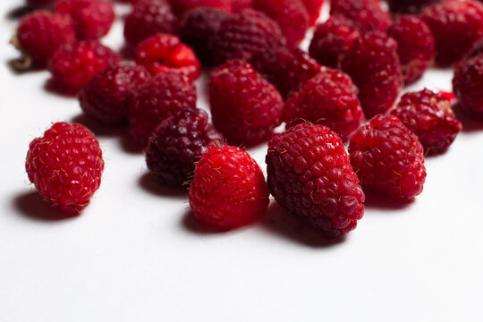 Close-up studio photo of fresh raspberries spread on the white background.
