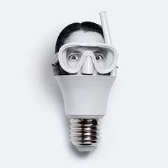 Close-up of light bulb with male head wearing diving mask, isolated on white.