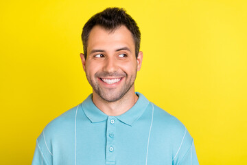 Photo of cunning brunet young man look empty space wear blue polo isolated on yellow color...