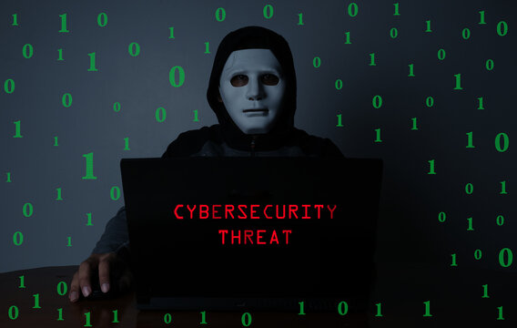 A low exposure and noise effect added picture of hacker with laptop insight, binary code and cybersecurity threat word. Hacking and cyber security threat concept.