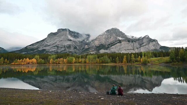 Young couple enjoying in Wedge pond with Rocky mountains in the morning at Kananaskis