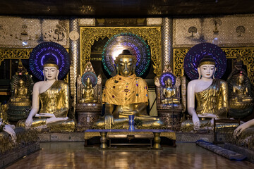 Beleuchtete Buddha-Figuren in einem Tempel der Shwedagon Pagode in Yangon bei Nacht - obrazy, fototapety, plakaty