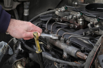 Worker fixing modern common rail diesel engine, closeup of hand with spanner tool, rail, pipeline and injectors