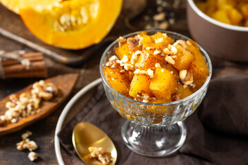 Traditional Turkish dish of baked pumpkin Kabak tatlisi in a glass bowl on a brown background. Delicious healthy dessert