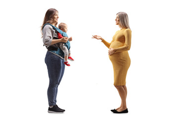 Fototapeta premium Full length profile shot of a young pregnant woman talking to a mother with a baby in a carrier