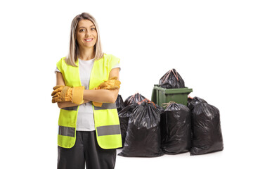 Woman waste collector in a uniform posing in front of a pile of bags