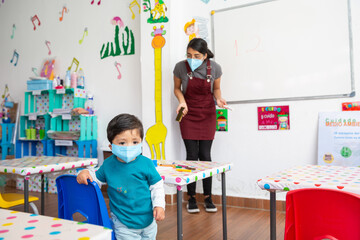 mexican teacher teaching in school with face mask to mexican baby