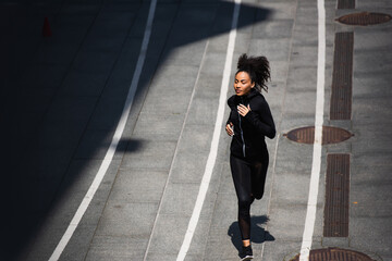 High angle view of young african american sportswoman jogging on running track