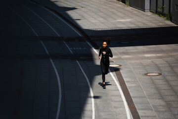 Fototapeta na wymiar High angle view of african american sportswoman running on track outdoors