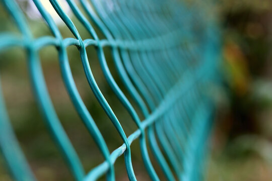Steel grating fence of soccer field,Metal fence wire with grass in the background. - Powered by Adobe