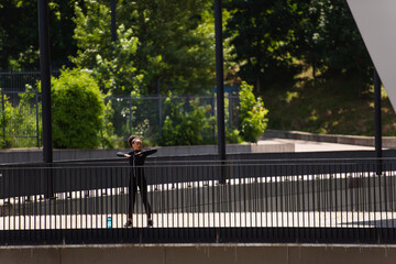 Young african american woman exercising near sports bottle on bridge on urban street