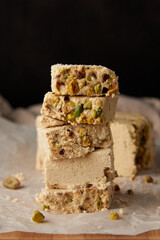 Organic halva with pistachios on a wooden surface. Traditional middle eastern sweets. Jewish, turkish, arabic oriental national dessert. Turkish delight concept. Natural vegan product. Copy space.