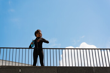 Low angle view of african american sportswoman with sports bottle training on bridge