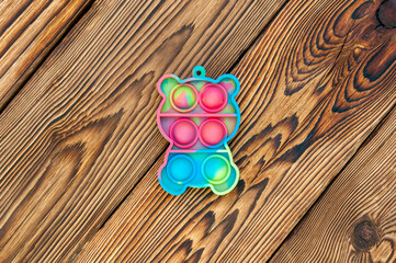 New popular silicone colorful antistress pop it toy for child on wooden background. View from above. Simple dimple.