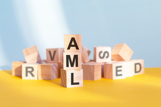 wooden cubes with letters AML arranged in a vertical pyramid, yellow background