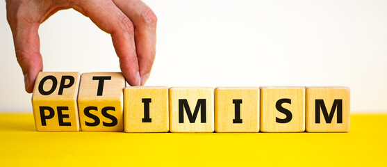 Pessimism or optimism symbol. Businessman turns cubes and changes the word 'pessimism' to 'optimism'. Beautiful yellow table, white background. Business, optimism or pessimism concept. Copy space.