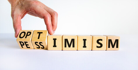 Pessimism or optimism symbol. Businessman turns cubes and changes the word 'pessimism' to 'optimism'. Beautiful white table, white background. Business, optimism or pessimism concept. Copy space.