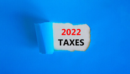 2022 taxes new year symbol. Words '2022 taxes' appearing behind torn blue paper. Beautiful blue...