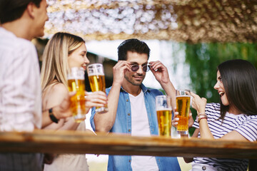 Group of young people drink beer and have fun at a summer bar