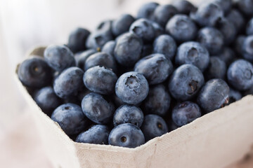 A lot of beautiful juicy fresh summer blueberries in a brown bag on a light background