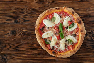 Oven baked pizza with buffalo mozzarella, parmigiano-reggiano cheese, basil and anchovies. Traditional italian dish on white wood textured table background. Close up, copy space, top view.