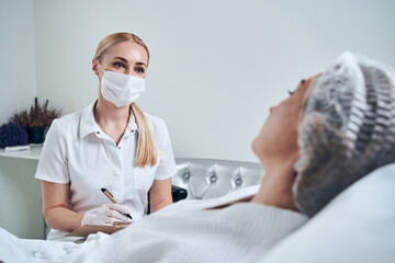 Cheerful blonde woman making notes during consultation