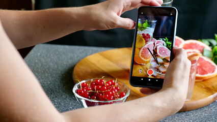Woman takes pictures of grapefruit lemonade on the phone. Flat lay a refreshing cold drink in summer