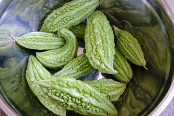 A lot of bitter melons after harvesting in a inox bucket