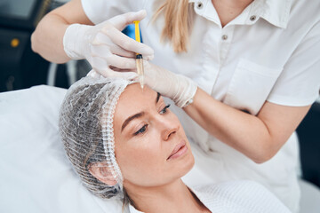 Kind female person doing injection into forehead