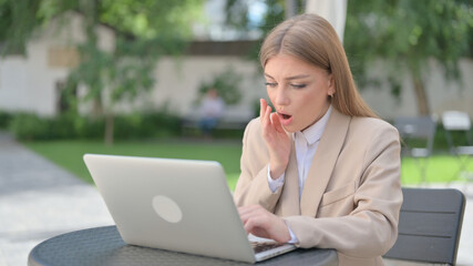 Businesswoman Feeling Shock while using Laptop in Outdoor Cafe